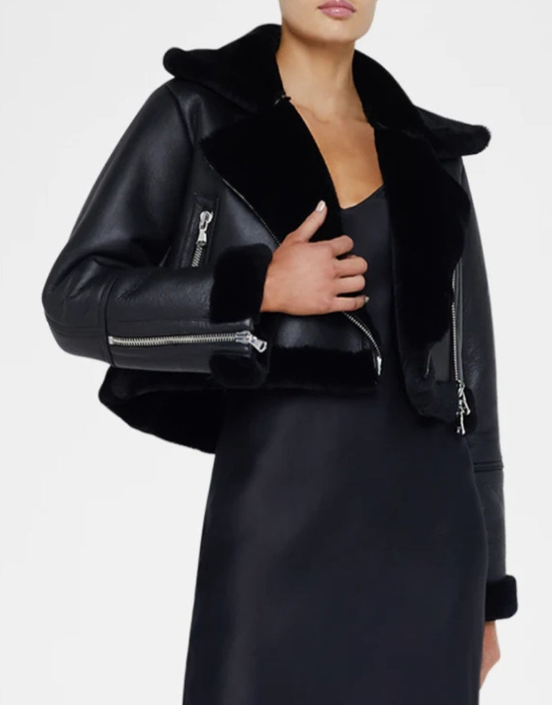 Women's black cropped shearling jacket with plush fur collar, asymmetrical zipper closure, and zippered pockets stylish and warm winter outerwear.