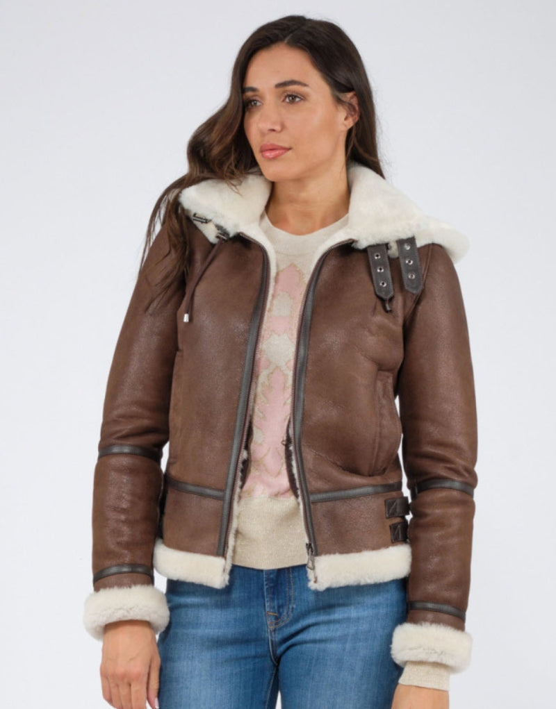 Brown leather shearling-lined jacket with zip-up hoodie, adjustable buckle collar, and white fur trim on cuffs and hem stylish and warm outerwear for winter.