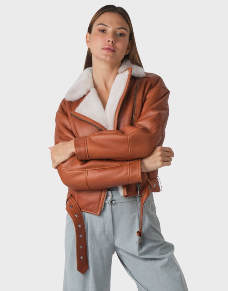 Women's brown faux leather shearling biker jacket with plush white fur lining, asymmetrical zipper closure, and belted waist perfect for winter fashion.
