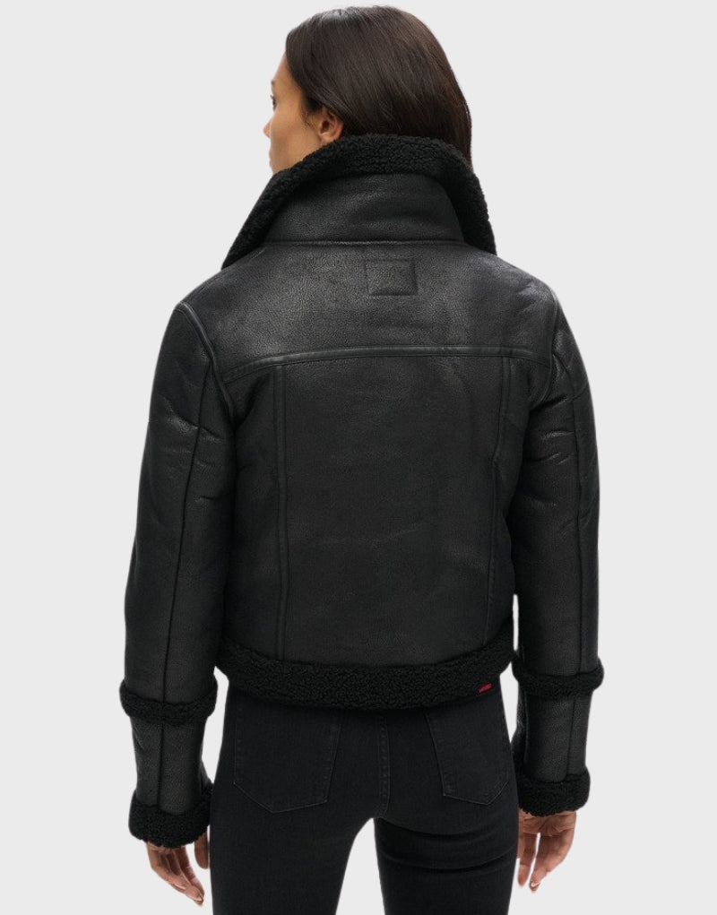 Back view of a black leather shearling aviator jacket for women featuring a plush fur collar and hem, highlighting premium craftsmanship.