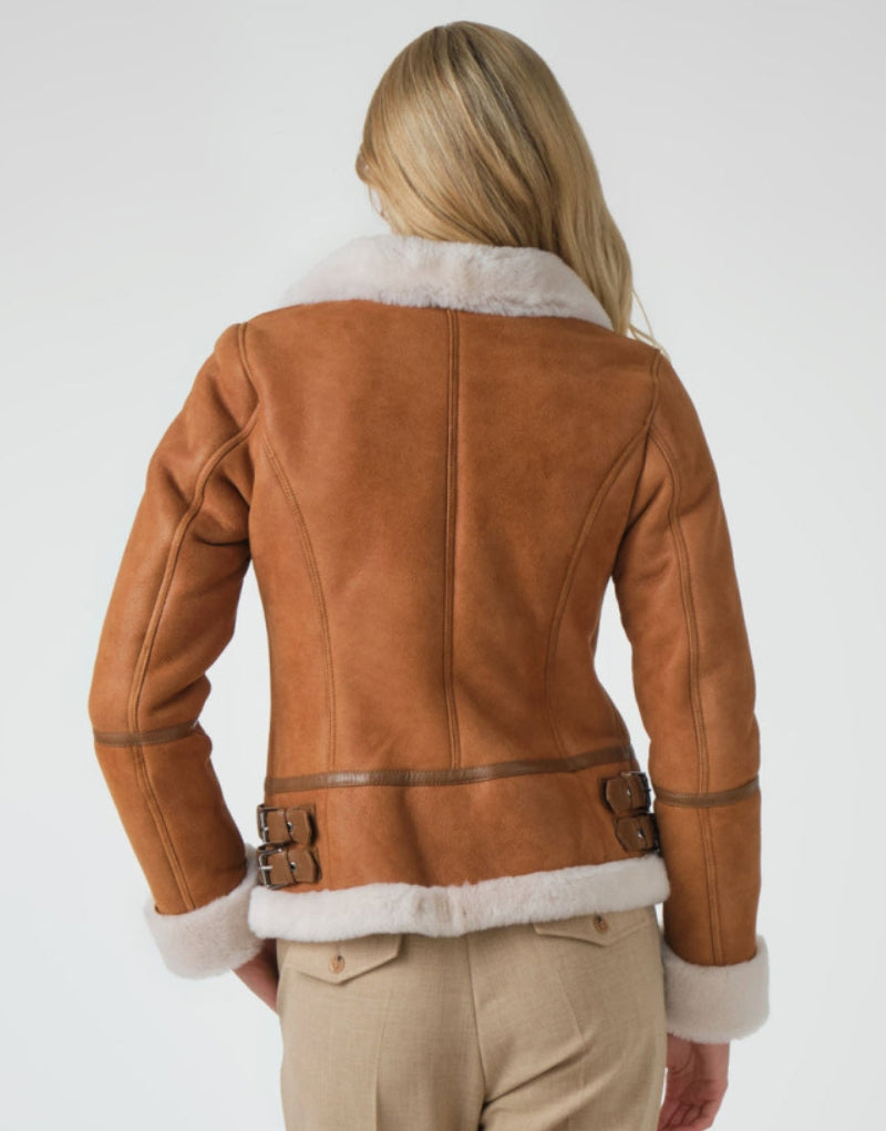 Women's tan leather shearling jacket with a plush white fur collar, adjustable side buckles, and soft fur-lined cuffs designed for warmth and style.