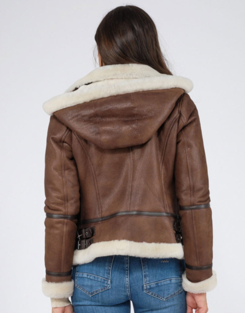 Back view of women's brown leather shearling jacket with white fur trim, attached hood, and adjustable waist straps stylish and warm winter outerwear.